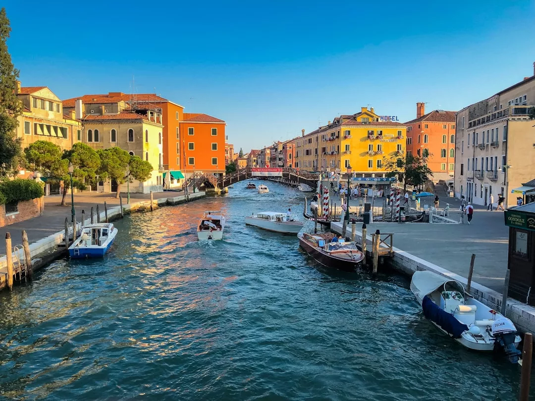 Ein Kanal auf Mallorca, an dessen Ufern mehrere Boote anlegen, gesäumt von farbenfrohen Gebäuden und einem klaren blauen Himmel.