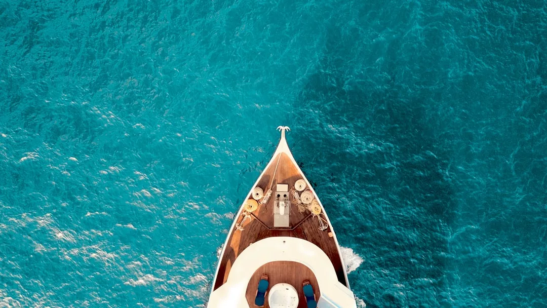 Luftaufnahme des Buges einer Yacht, der durch das strahlend blaue Meerwasser Mallorcas schneidet.