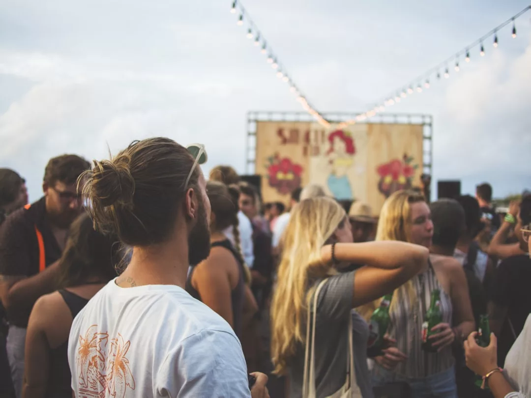 Bei einem Festival oder Konzert auf Mallorca versammelt sich eine Menschenmenge im Freien, mit Lichterketten über den Köpfen und einer dekorierten Bühne im Hintergrund.