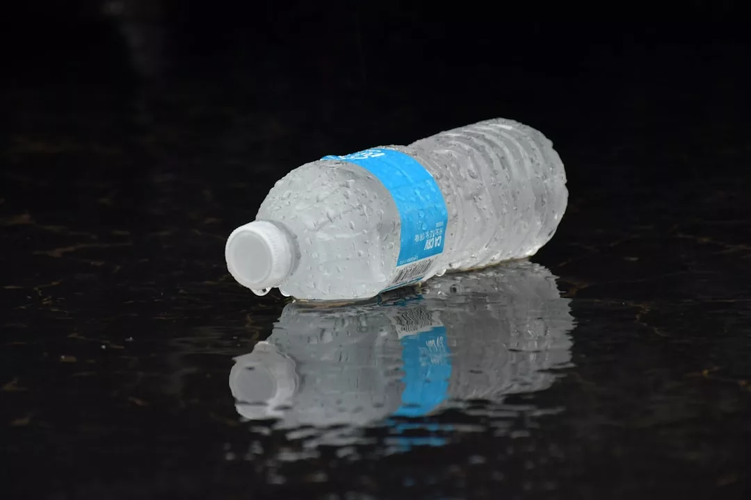 Eine Plastikwasserflasche mit blauem Etikett liegt seitlich auf einer nassen, spiegelnden Oberfläche und weckt Erinnerungen an sonnendurchflutete Tage auf Mallorca.