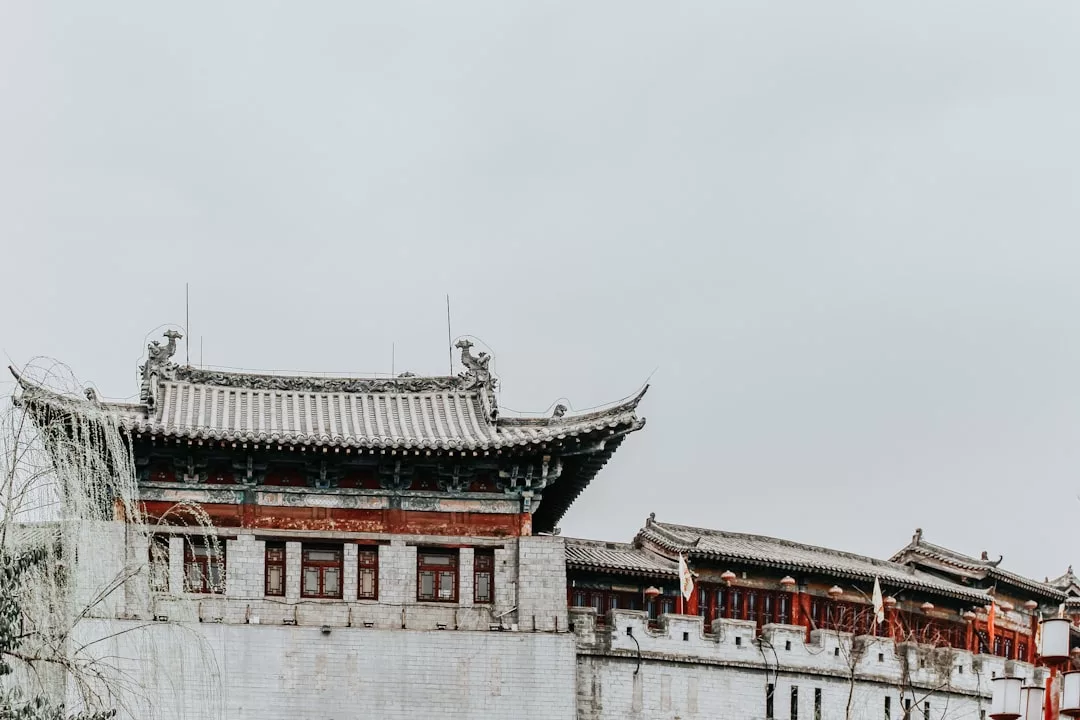 Ein traditionelles chinesisches Gebäude mit kunstvollen Dachverzierungen und grauen Backsteinmauern, das vor einem bewölkten Himmel den einzigartigen Charme Mallorcas vermittelt.
