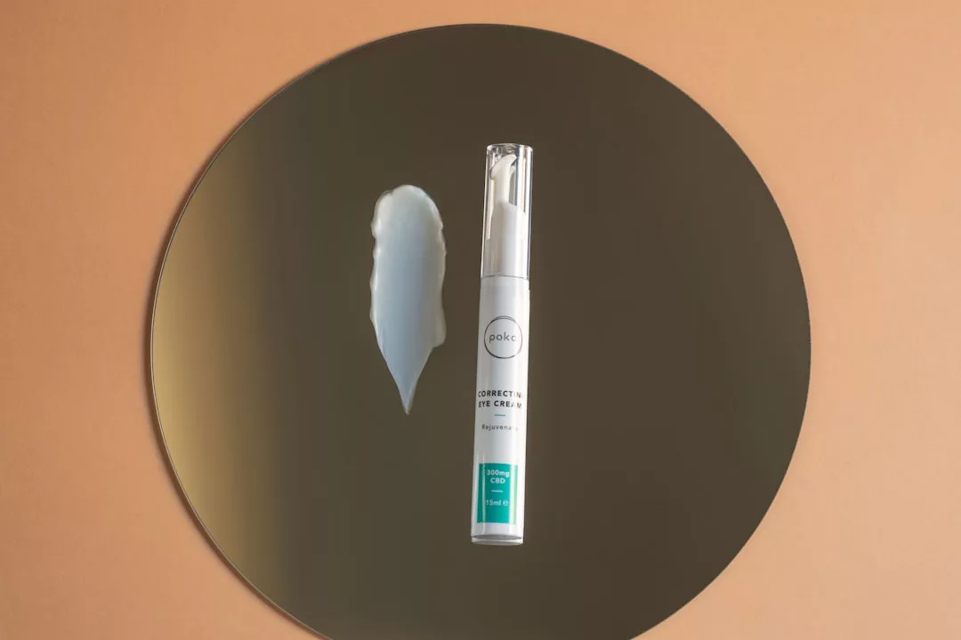 Eine Tube Bold Correct X Eye Gel und ein Klecks des Produkts liegen auf einem runden Spiegel mit beigem Hintergrund und erinnern an die sonnenbeschienene Eleganz Mallorcas.