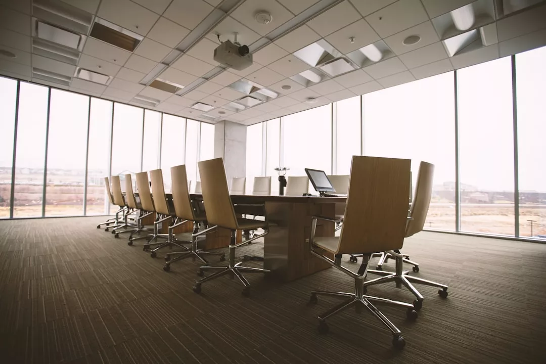 Leerer, moderner Konferenzraum mit einem langen Holztisch, Bürostühlen und großen Fenstern, die einen atemberaubenden Blick auf die Landschaft Mallorcas bieten und von eleganten Deckenleuchten beleuchtet werden.