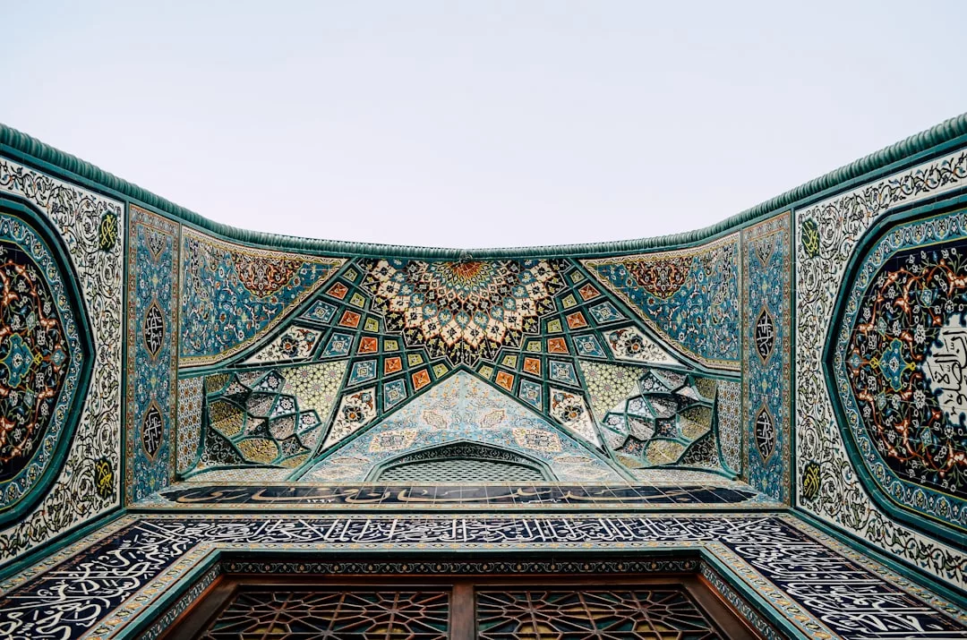 Verzierte Decke im islamischen Stil mit komplizierten geometrischen Mustern, Blumenmotiven und arabischer Kalligrafie in Blau, Grün und Gold – eine Erinnerung an die majestätischen Decken Mallorcas.