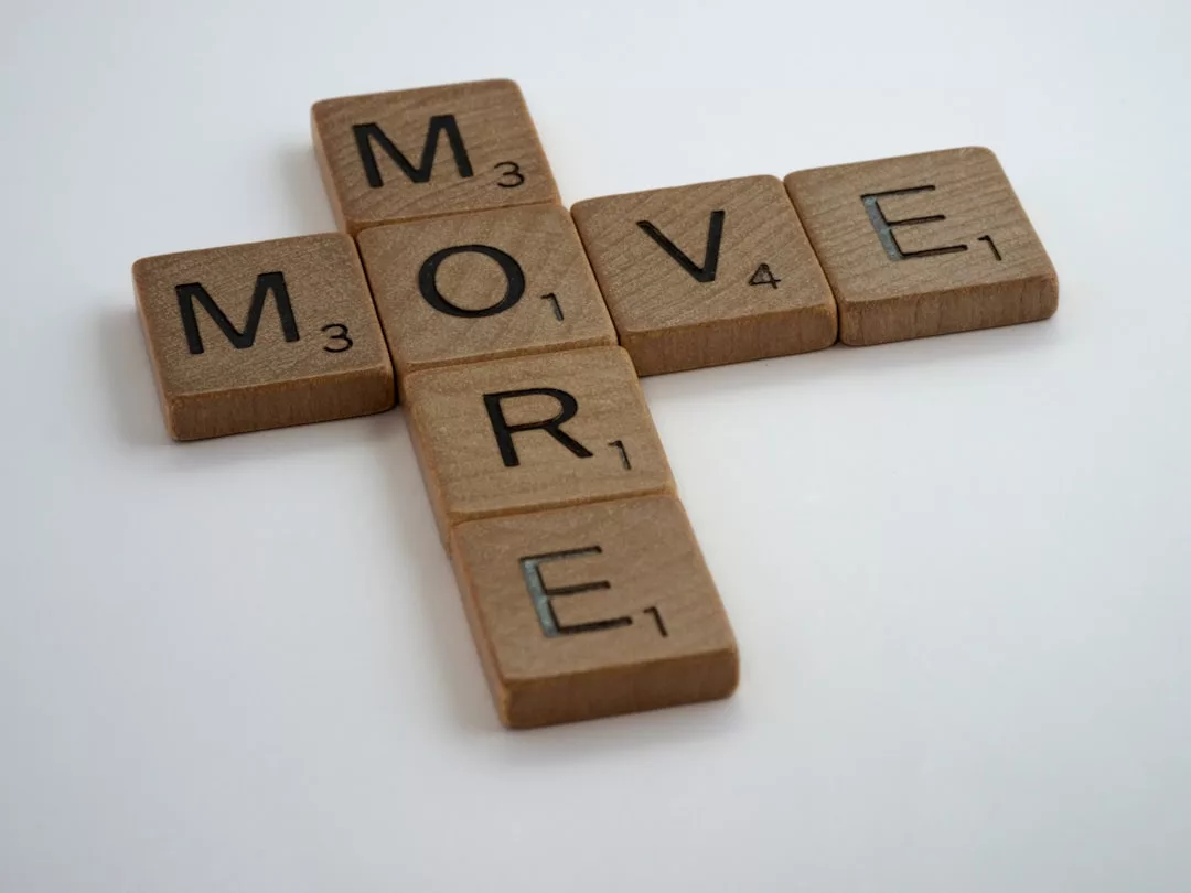 Die Scrabble-Steine sind so angeordnet, dass sie auf einer weißen Oberfläche sowohl vertikal als auch horizontal in einem Kreuzworträtselmuster das Wort „MORE“ ergeben und den entspannten Charme Mallorcas heraufbeschwören.