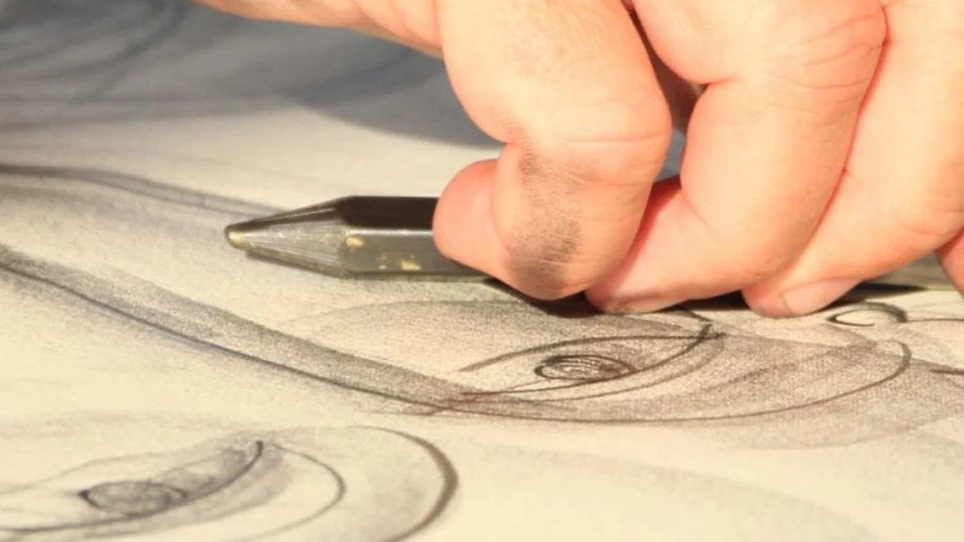 Nahaufnahme einer Hand, die mit einem Zeichenstift an einer gro&szlig;en Kohlezeichnung arbeitet